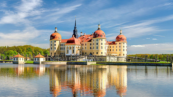 Schloss Moritzburg Das Schloss Moritzburg vor einem blauen Himmel. Das Schloss spiegelt sich im Teich.